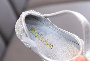 Primer plano de los detalles de diamantes en zapatos de princesa Mary Jane plateados para niña
