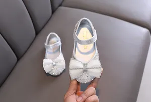 Detailansicht von silbernen Mädchen-Prinzessin-Schuhen mit Strassschleife und Perlen.