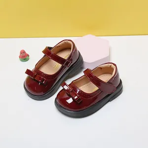 Detail view of burgundy patent leather toddler girl shoes with bow and soft sole.