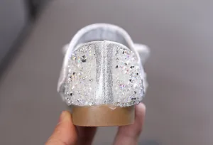 Makro-Detail der glitzernden Strass- und Perlenferse bei eleganten Mädchenschuhen