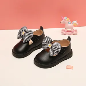 Detailed shot of black baby girl Mary Janes with a decorative houndstooth bow and daisy