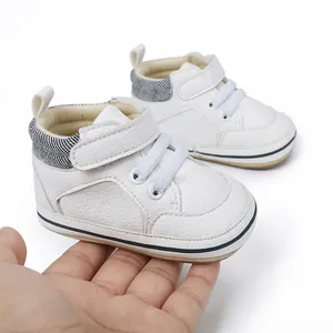 Nahaufnahme von weichen weißen Leder-Lauflernschuhen für Babys in der Hand gehalten