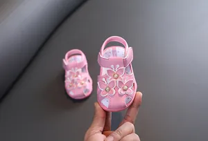 Gros plan de sandale rose pour bébé avec papillons 3D et perles fines.