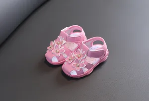 Détail de sandales roses pour bébé avec papillons et perles au centre