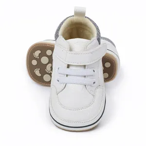 Detailed view of white infant walking shoes with textured leather and non-slip sole.