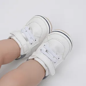 Close-up view of white infant walking shoes featuring soft PU leather and velcro straps
