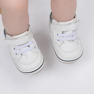 Close-up view of white leather baby pre-walker shoes with velcro strap and soft sole.