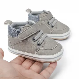Detail eines grauen Baby-Lauflernschuhs aus Leder mit Klettverschluss, Hand als Maßstab.
