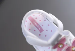 Gros plan de la semelle d'une sandale bébé avec cœurs roses et étiquette Fashion