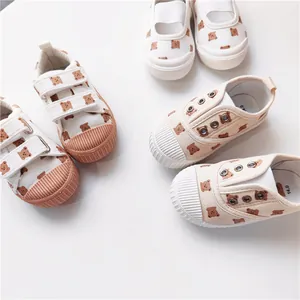 Detailansicht von cremefarbenen Kinderschuhen mit Bärenprint und Gummikappe.