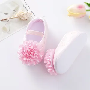 Detail view of pink baby princess shoes featuring large satin flower decorations.