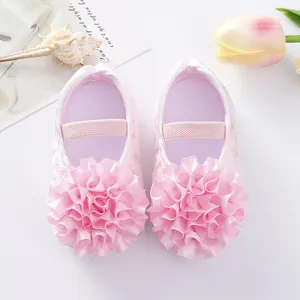 Close-up detail of pink baby princess shoes featuring large ruffled fabric flower accents