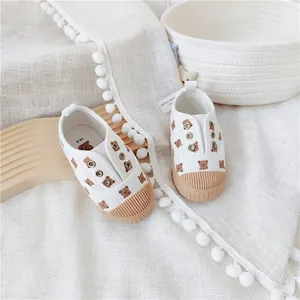Detailaufnahme von weißen Kinder-Stoffschuhen mit süßem Bärenmuster und Muschelzehen-Design