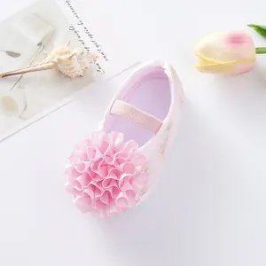 Close-up detail of pink baby princess shoe with large ruffled flower and soft sole.