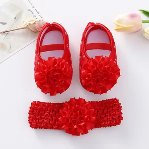 Détail de chaussures de princesse rouges pour bébé avec fleurs et bandeau assorti.