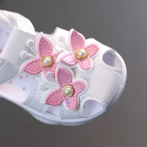 Gros plan de sandales blanches pour bébé fille avec papillons roses et perles décoratives