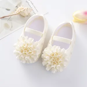 Close-up of adorable white baby princess shoes with large ribbon flower decor and soft sole.