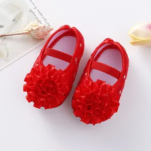 Detail view of red infant princess shoes with large ruffled flower and soft sole