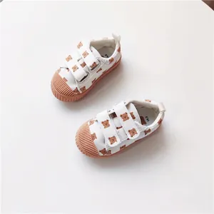 Detailansicht weißer Kinder-Segeltuchschuhe mit Bärenmuster und Muschelzehen-Design.