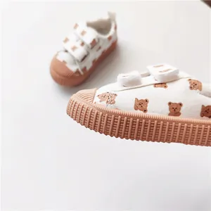 Makrodetail des braunen Bärendrucks und der Gummisohle an weißen Kinder-Canvas-Sneakern.