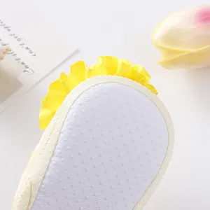 Macro detail view of the anti-slip soft sole on yellow ruffled baby princess shoes.