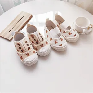Detail von cremefarbenen Kinder-Canvas-Schuhen mit Bärenprint und Muschelzehenkappe.