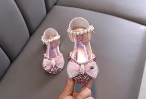 Dettaglio di scarpe da principessa rosa per bambine con strass e fiocco di perle