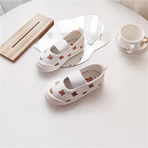 Nahaufnahme von weißen Kinder-Segeltuchschuhen mit Bärenmuster und Shell-Toe-Design