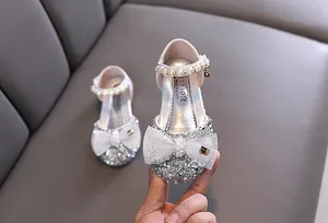 Vista dettagliata di scarpe da principessa con paillettes argento e cinturino di perle