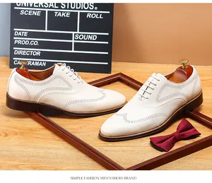 Detailed view of white business casual men's dress shoes with brogue wingtip patterns.