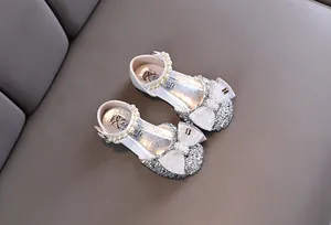 Dettaglio scarpe da principessa glitter argento con cinturino di perle e fiocco di pizzo