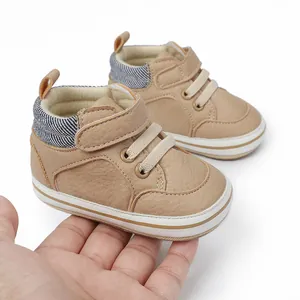 Detailansicht der khakifarbenen Baby-Lauflernschuhe in der Hand zur Größenanzeige