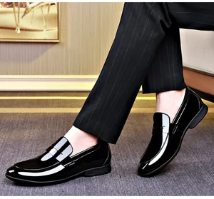 Vista laterale di mocassini da uomo in vernice nera lucida indossati con pantaloni gessati