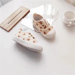 Detailansicht cremefarbener Kinder-Stoffschuhe mit süßem Bärenmuster und Muschelzehe