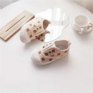 Nahaufnahme von süßen Kinder-Stoffschuhen mit Bärenprint, Muschelzehe und weicher Sohle.