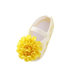 Adorable yellow baby girl princess shoes featuring a large ribbon flower and soft fabric soles