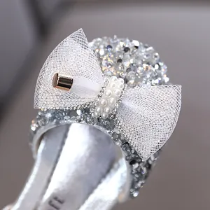 Primo piano di scarpe da principessa argento con un grande fiocco di pizzo e perle