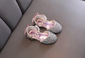 Primo piano di scarpe da principessa rosa glitterate per bambine con perle.