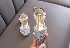 Primo piano di scarpe da principessa glitterate per bambina con perle e fiocco
