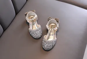 Scarpe da principessa in argento glitterato per bambina con cinturini di perle e fiocco.