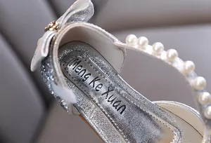 Dettaglio ravvicinato di scarpe da principessa argento glitterate con cinturino di perle