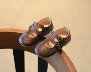 Detail of brown girl's Mary Jane shoes with brogue patterns and double buckles.