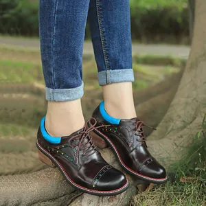 Detailed view of brown handmade leather shoes with colorful star patterns on a tree root.