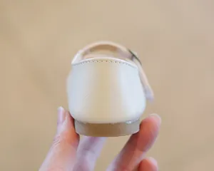 Detailed view of the heel and stitching on a beige leather girls' Mary Jane shoe.