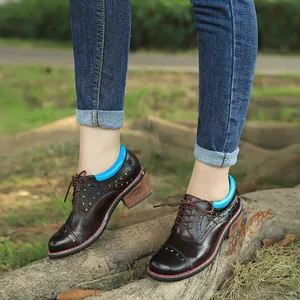 Close-up detail of handcrafted brown leather block heel oxfords with colorful star patterns