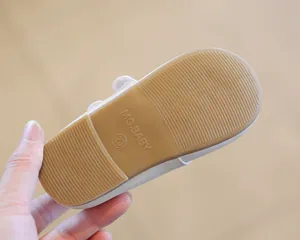 Macro view showing the non-slip rubber sole detail of a girl's white leather shoe