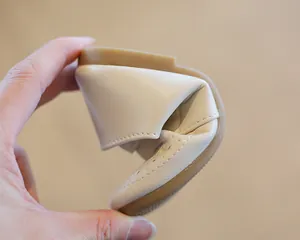 Extremely flexible beige children's Mary Jane leather shoe being folded to show softness