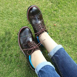 Close-up view of brown leather lace-up shoes with colorful star details on green grass