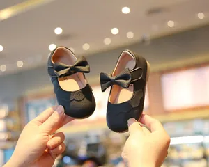 Nahaufnahme von eleganten schwarzen Baby-Mädchen-Schuhen mit Schleife und Wellenrand
