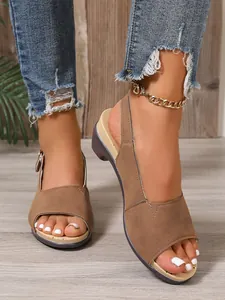 Close-up van bruine sleehak-sandalen met open teen, gedragen met gerafelde spijkerbroek en enkelband